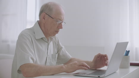 Un-Anciano-Está-Trabajando-Remotamente-Escribiendo-Y-Enviando-Mensajes-Por-Correo-Electrónico-Usando-Internet-En-Una-Computadora-Portátil-Quedándose-En-Casa